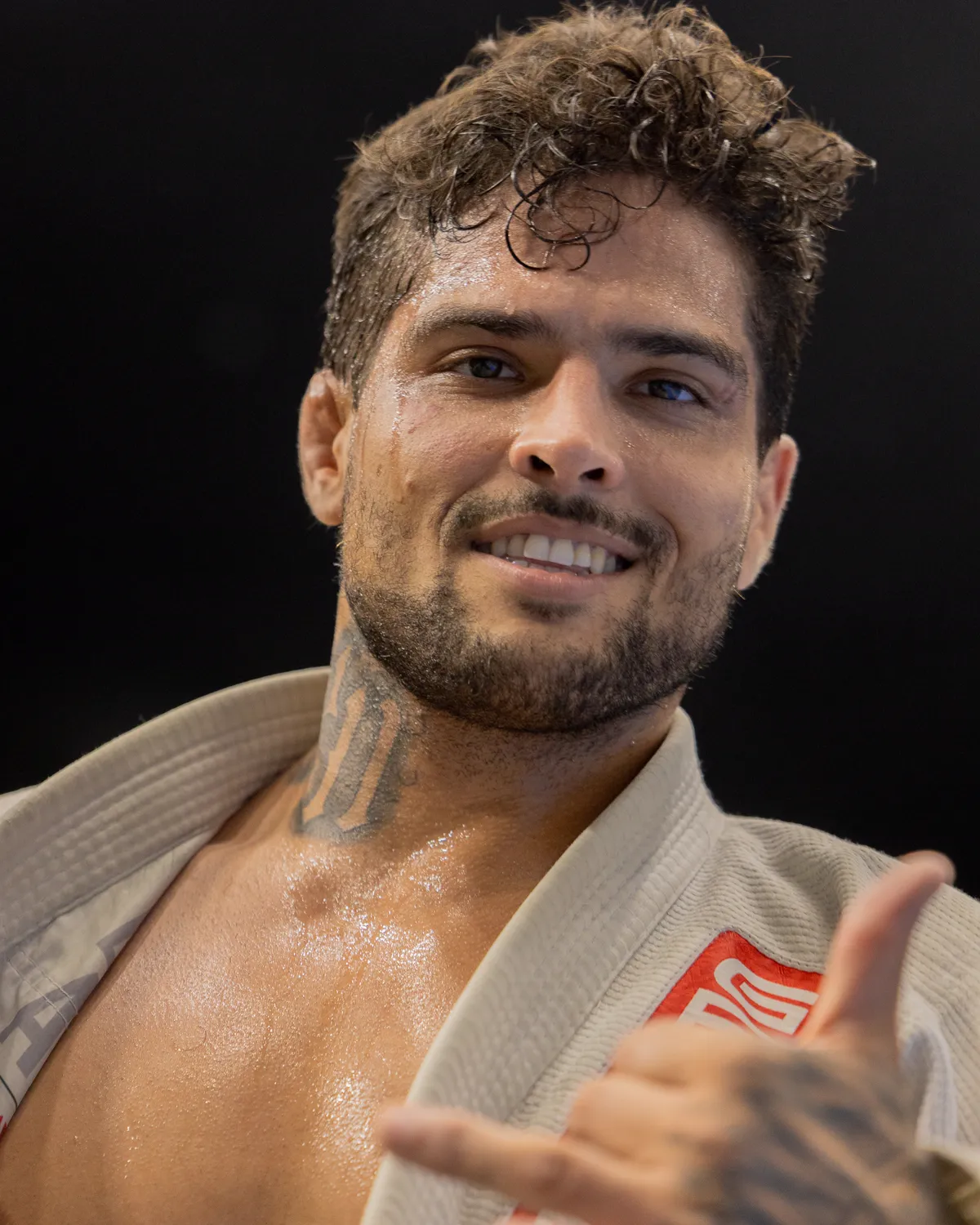 Daniel Teodoro, professor da Gracie Barra na Barra dos Coqueiros, de kimono, sorrindo e fazendo um aceno com a mão